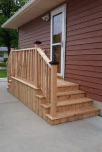 Small wooden porch off with two sets of stairs & railing