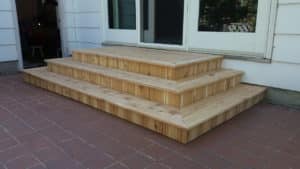 Small wooden custom-built 3 steps leading down from a house door