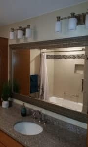 Bathroom remodel with grey speckled countertop & clean beige tiled shower