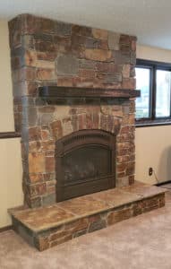 Custom floor-to-ceiling red, grey & beige large mixed stone fireplace