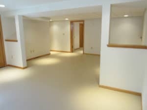 'After’ picture of finished basement with white walls & light wood trim