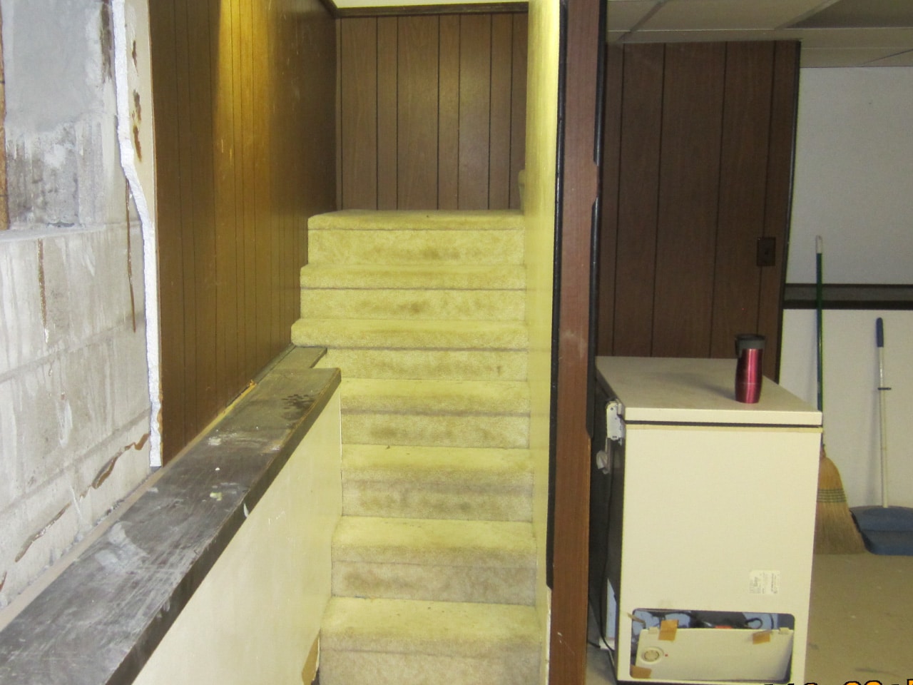 ‘Before’ picture of old carpeted stairs leading to basement