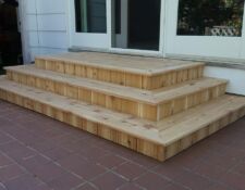 Small wooden custom-built 3 steps leading down from a house door