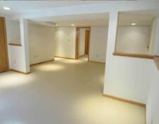 Bright, white-walled & light wood baseboard trim basement