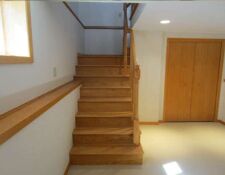 Newly constructed wooden stairs & railing lead to clean basement