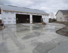 Driveway leading to unfinished 2-stall workshop covered in Tyvek