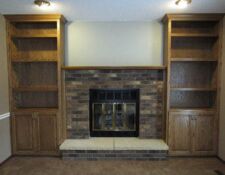 Two wooden built-in shelves on either side of a brick fireplace