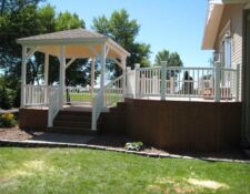 Large dark wood back porch with white railing & gazebo