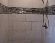 Large white ceramic tiled shower with thin shiny tile surround feature